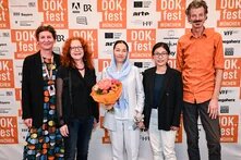DOK.fest Preisverleihung 2024 mit Menschen vor der DOK.fest Wand