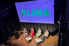 Podiumsdiskussion mit Banner im Hintergrund von "Nach uns das Klima"