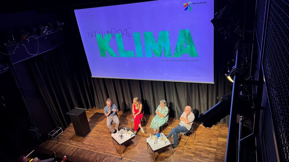 Podiumsdiskussion mit Banner im Hintergrund von "Nach uns das Klima"