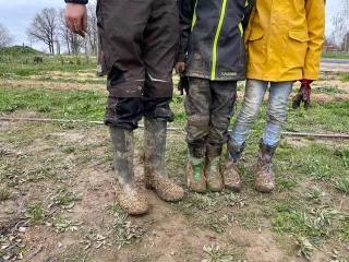 drei Personen mit geschmütze Gummistiefel auf dem Land